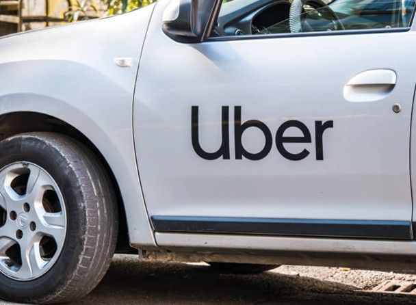 White Uber car with black logo on the door. White Uber car with black logo on the door.