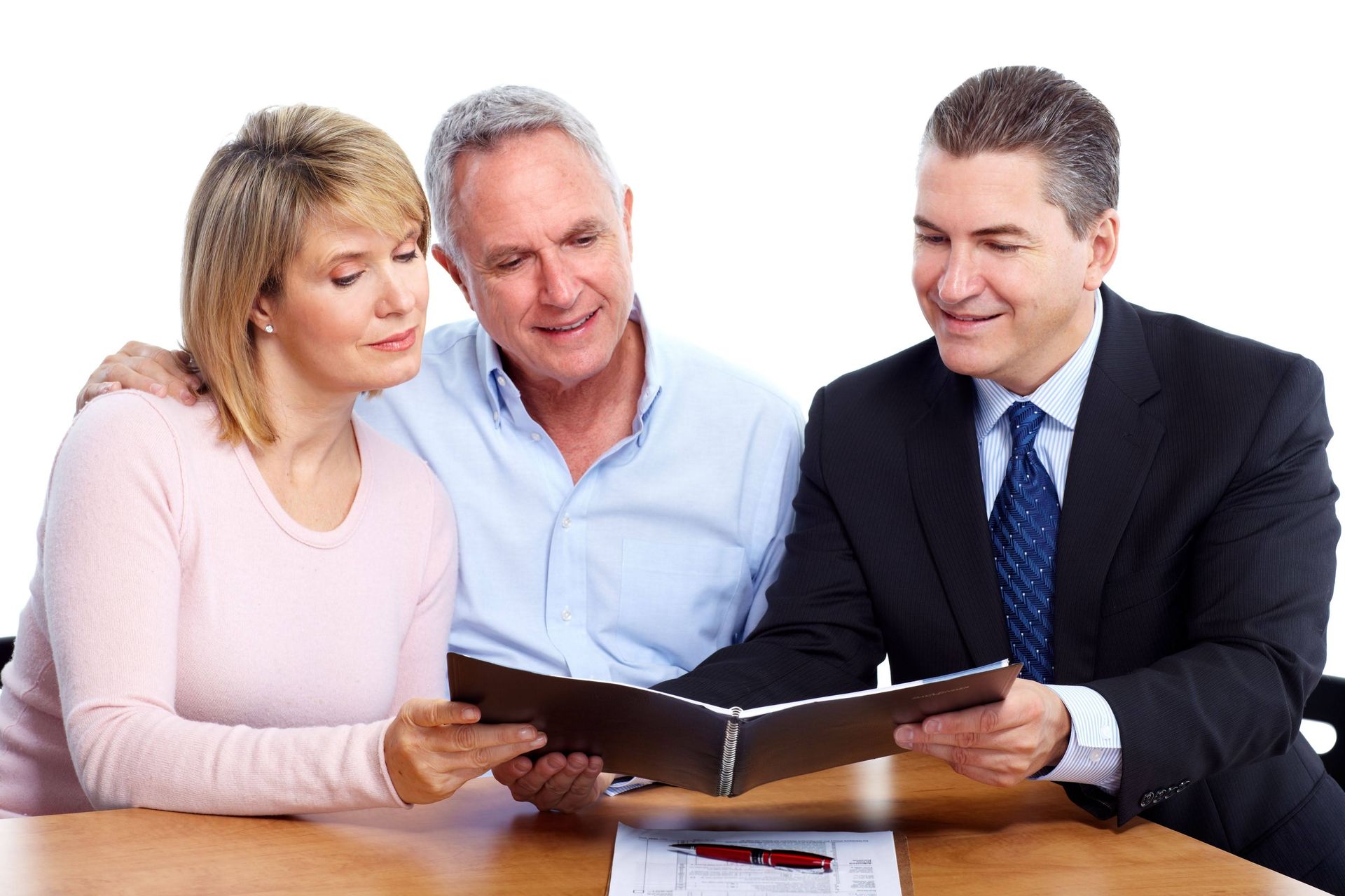 A man and a woman are sitting at a table looking at a book.