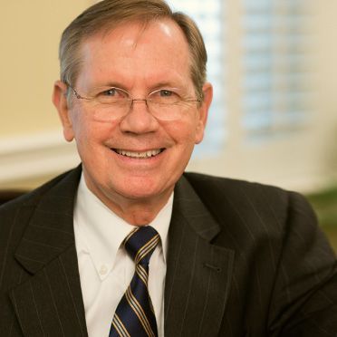 A man in a suit and tie is smiling for the camera