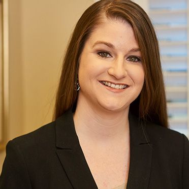 A woman in a black jacket is smiling for the camera.