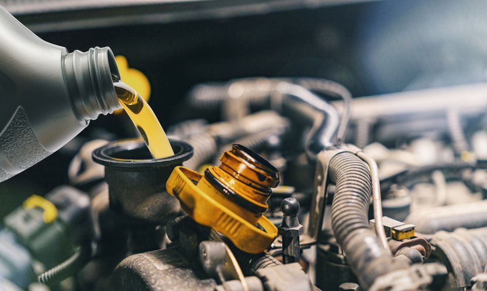 A Person is Pouring Oil Into a Car Engine — Fix-It Automotive in Unanderra, NSW