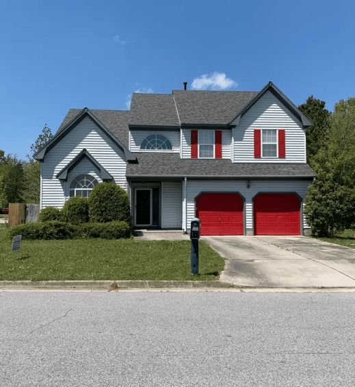 A white house with red garage doors and shutters