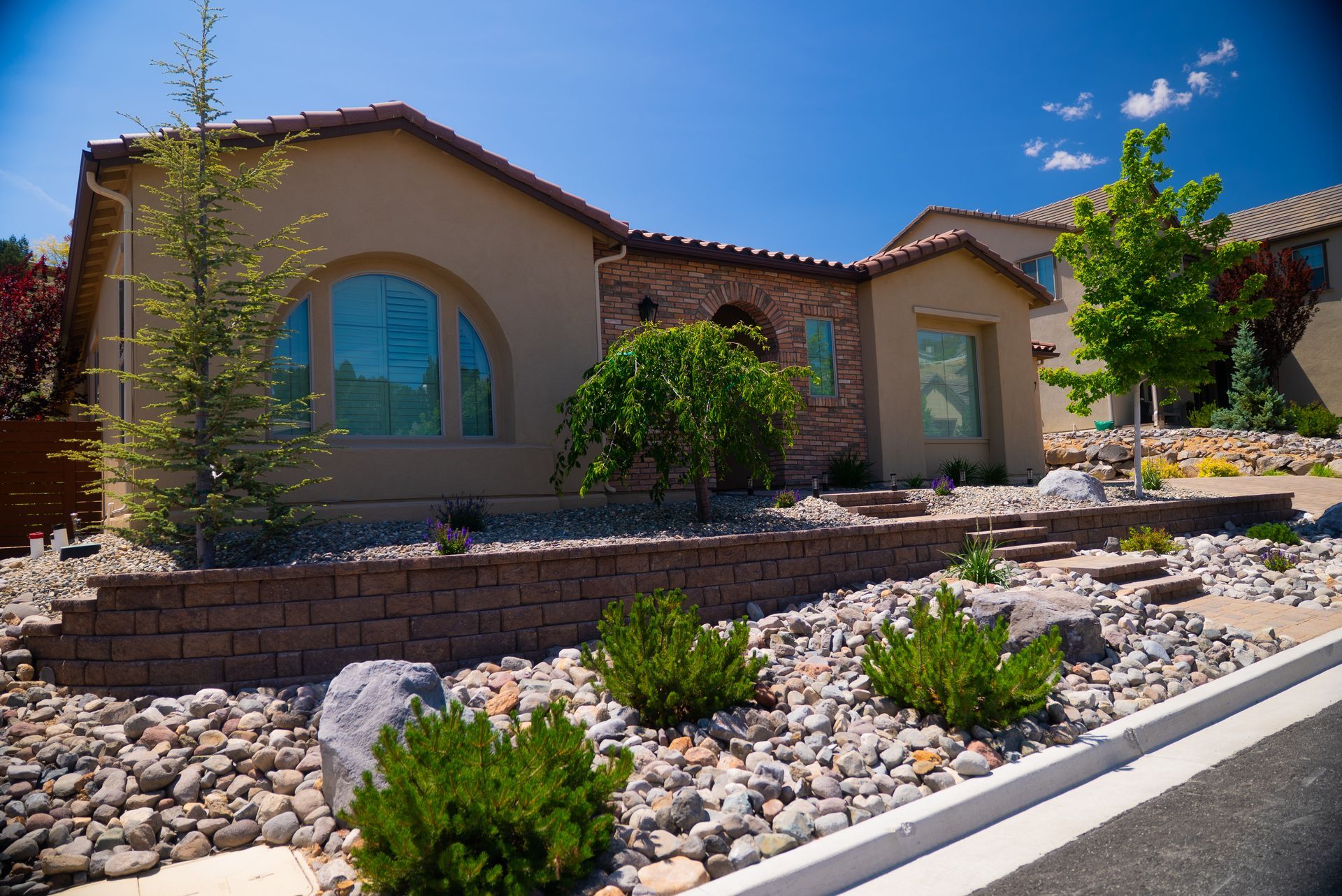 Beige house with arched window, stone accents, and drought-tolerant landscaping.