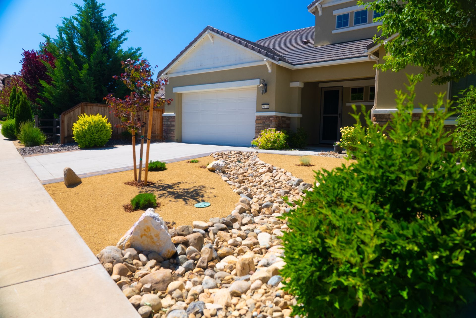 Beige house with a gravel and rock landscaped yard on a sunny day.