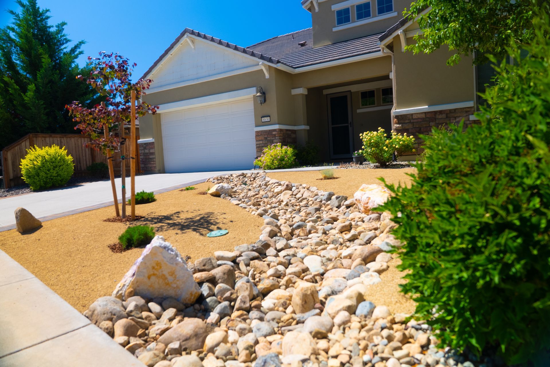 Beige house with a gravel and rock landscaped yard.