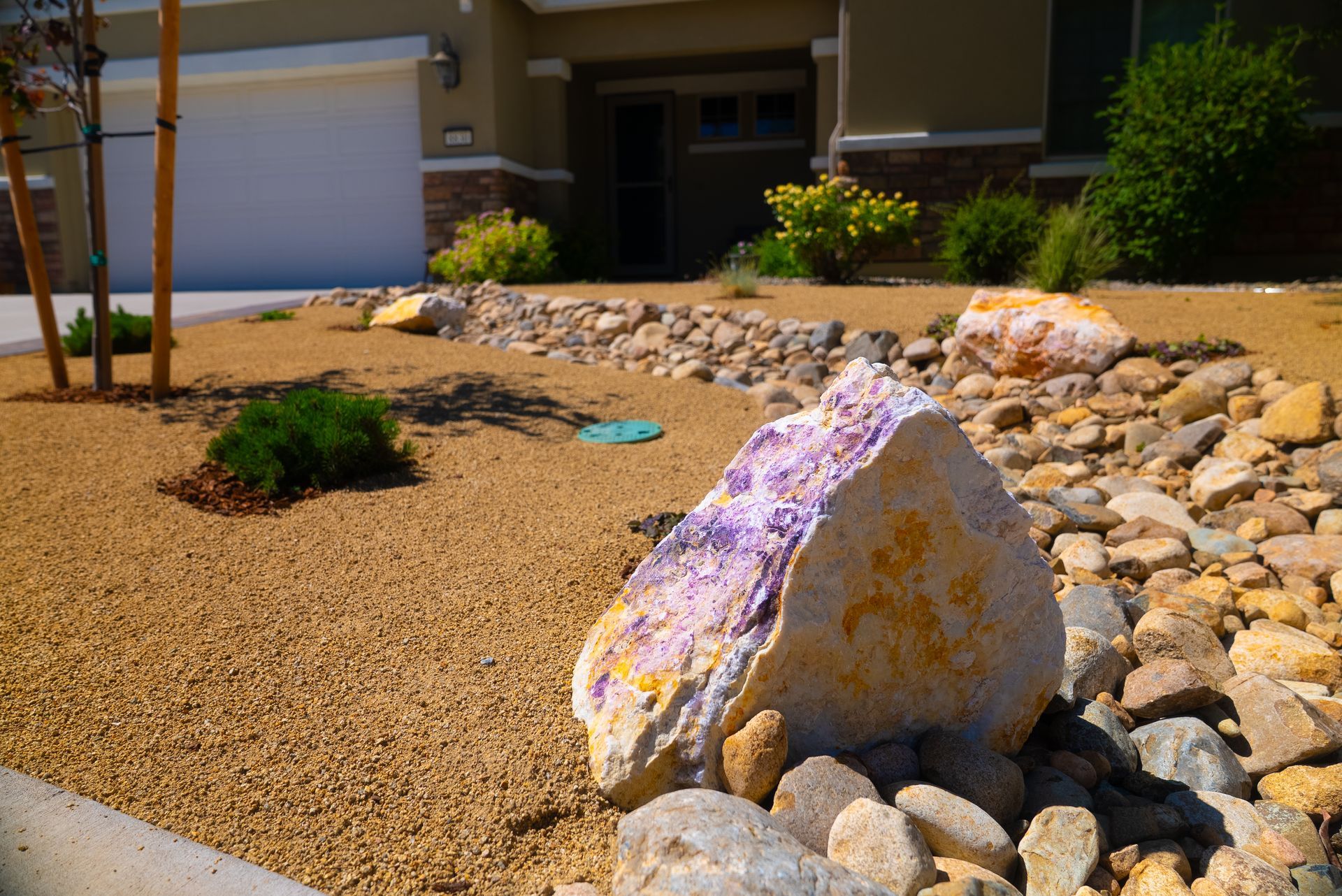 Front yard xeriscaping with tan gravel, rocks, and a large, colorful boulder.