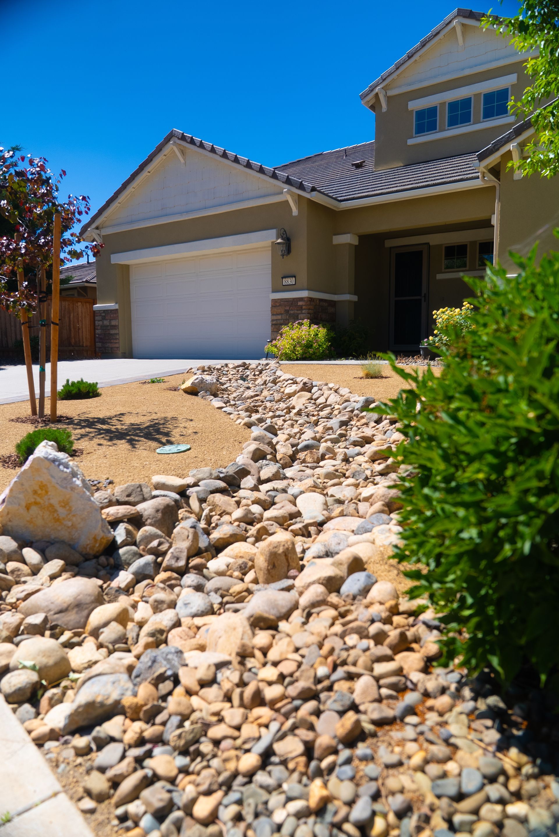 House with beige exterior, gravel landscape, and a path of stones in front.