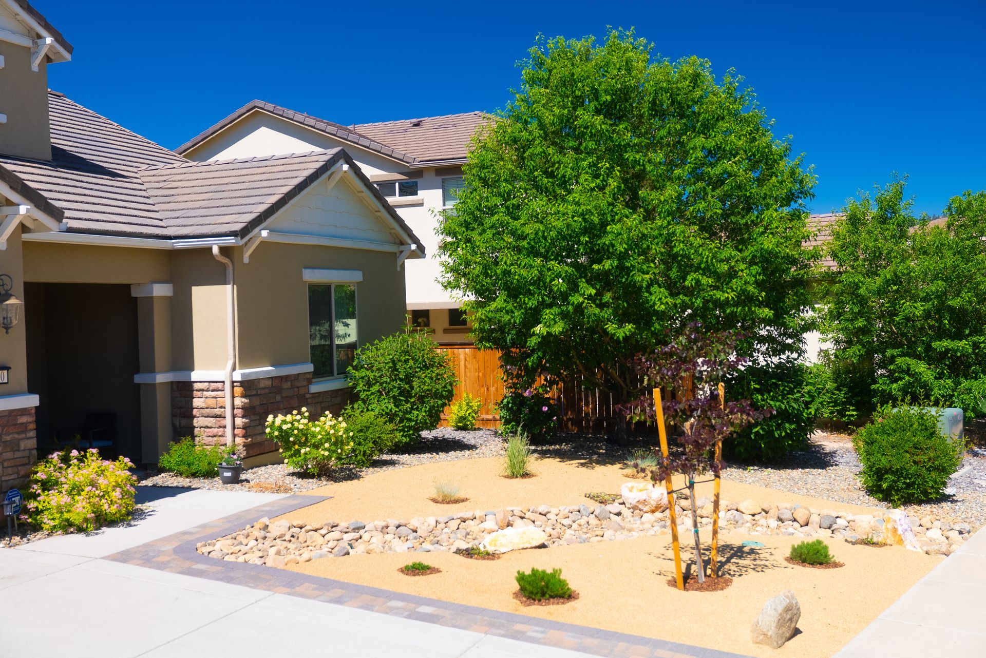 House with landscaped front yard, featuring drought-tolerant plants and decorative rock accents.