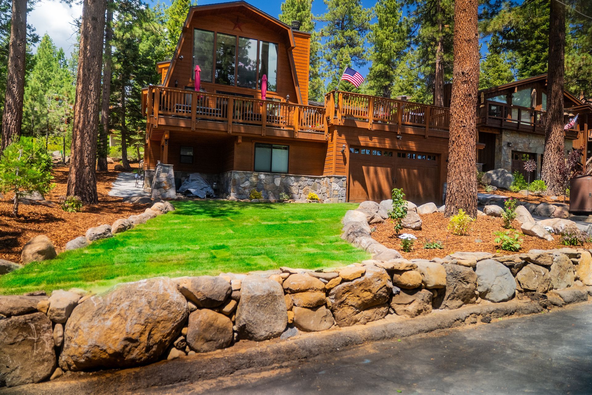 Brown wooden cabin with a sloping roof and a stone foundation, set among tall trees.