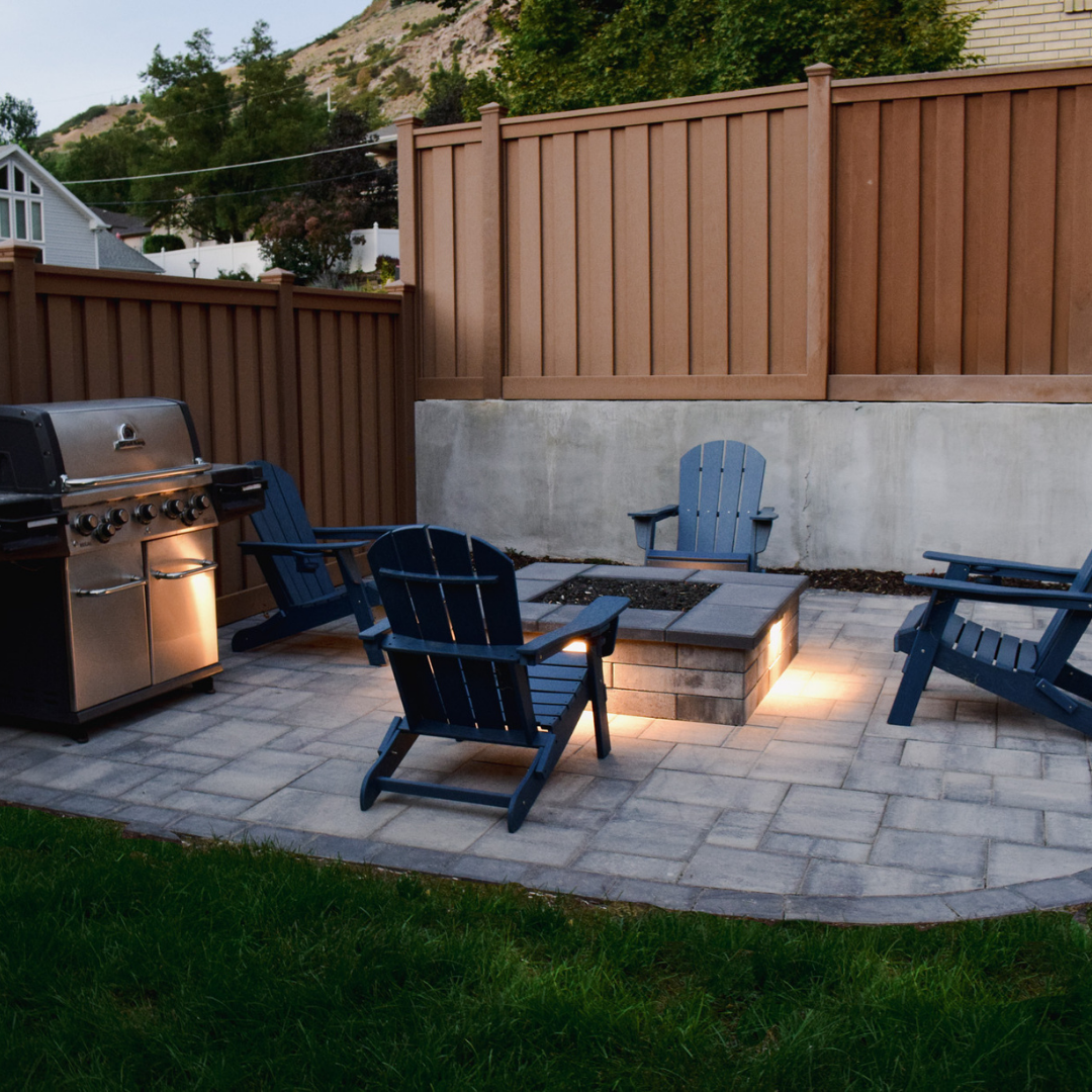 Stamped concrete patio with built-in fire pit and seating area in a Reno NV backyard during evening lighting