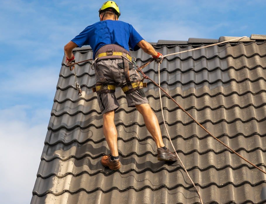 A Roofer in Safety Gear Working on a Tiled Roof — Expert Plumbing & Solar Services Bathurst in Kelso, NSW