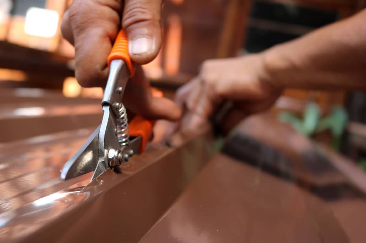 Person Using Metal Shears to Cut a Copper Roof Edge — Expert Plumbing & Solar Services Bathurst in Blayney, NSW