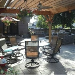 Outdoor patio with wooden pergola, metal chairs, and tables in bright sunlight