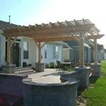 Patio with wooden pergola, outdoor seating, and a grill beside a house