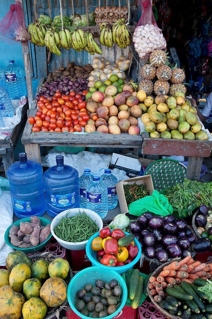 Colorful fruit and vegetable market stall with water jugs and baskets of produce