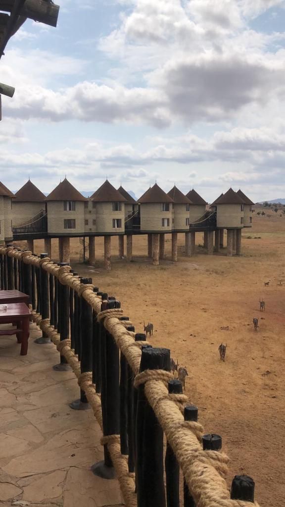 Curved wooden fence overlooking a dry village with raised huts under a cloudy sky