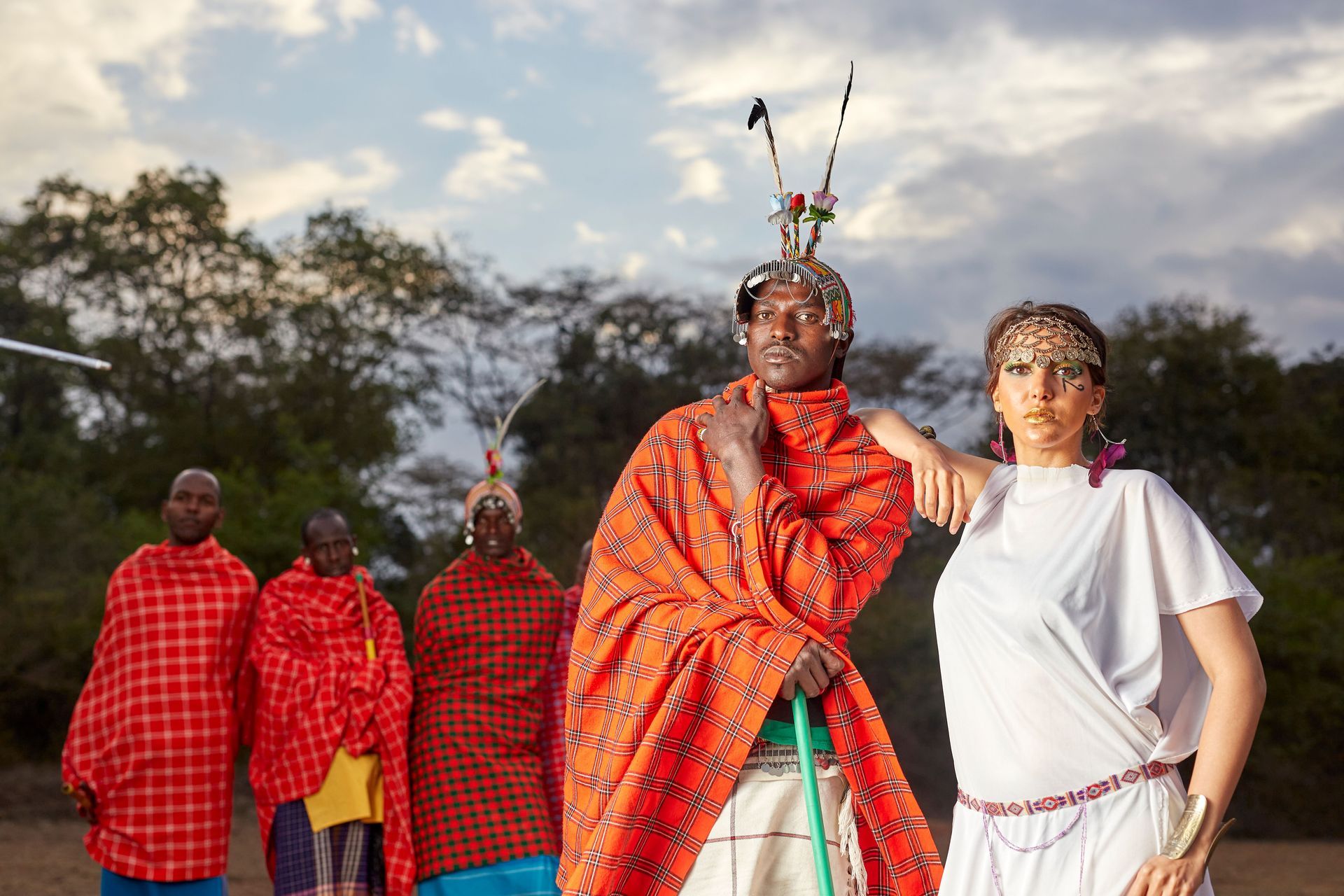 People in bright red and blue traditional clothing standing outdoors at a cultural gathering