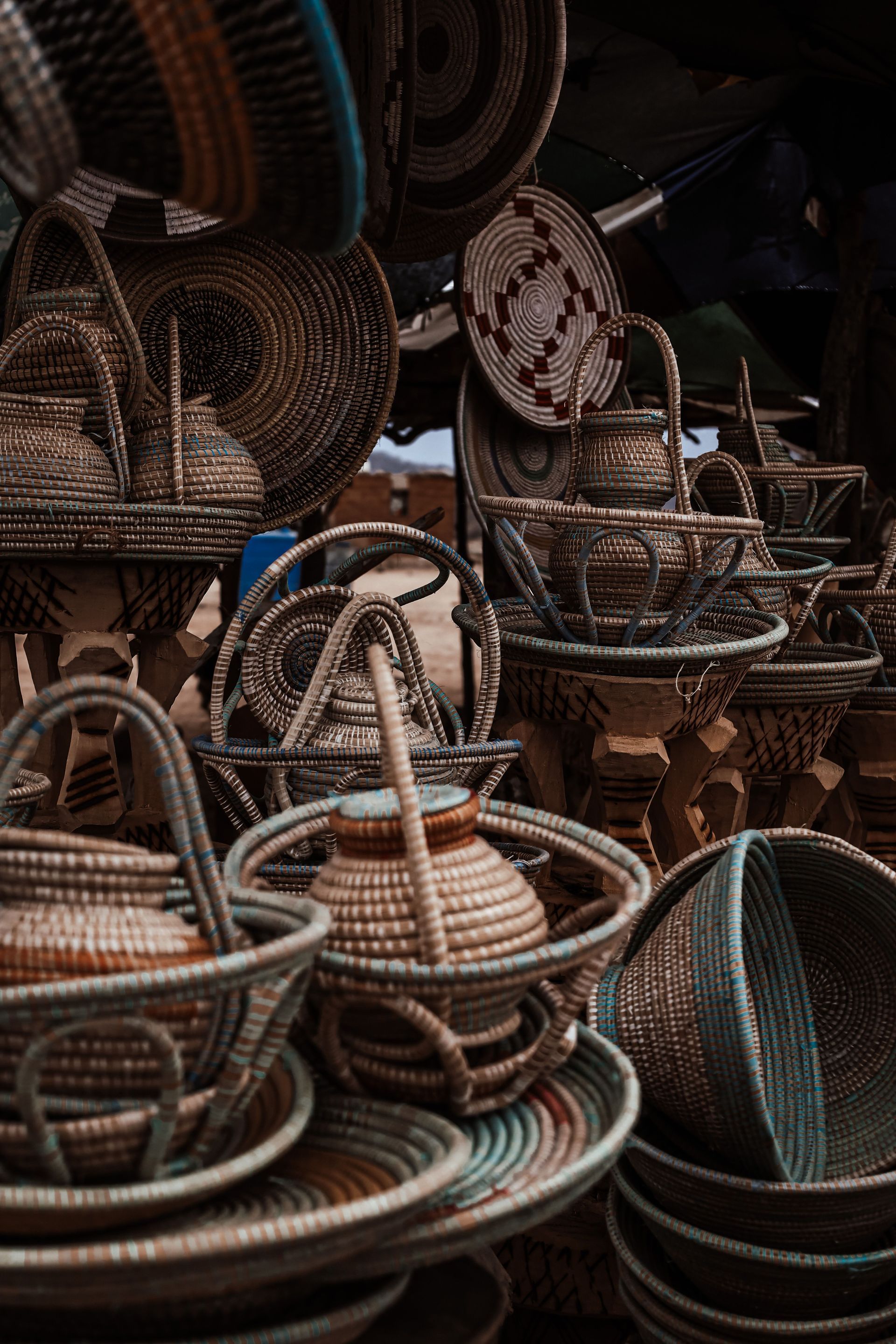 Stacks of woven wicker baskets in a market, mostly brown with one blue-accented basket.