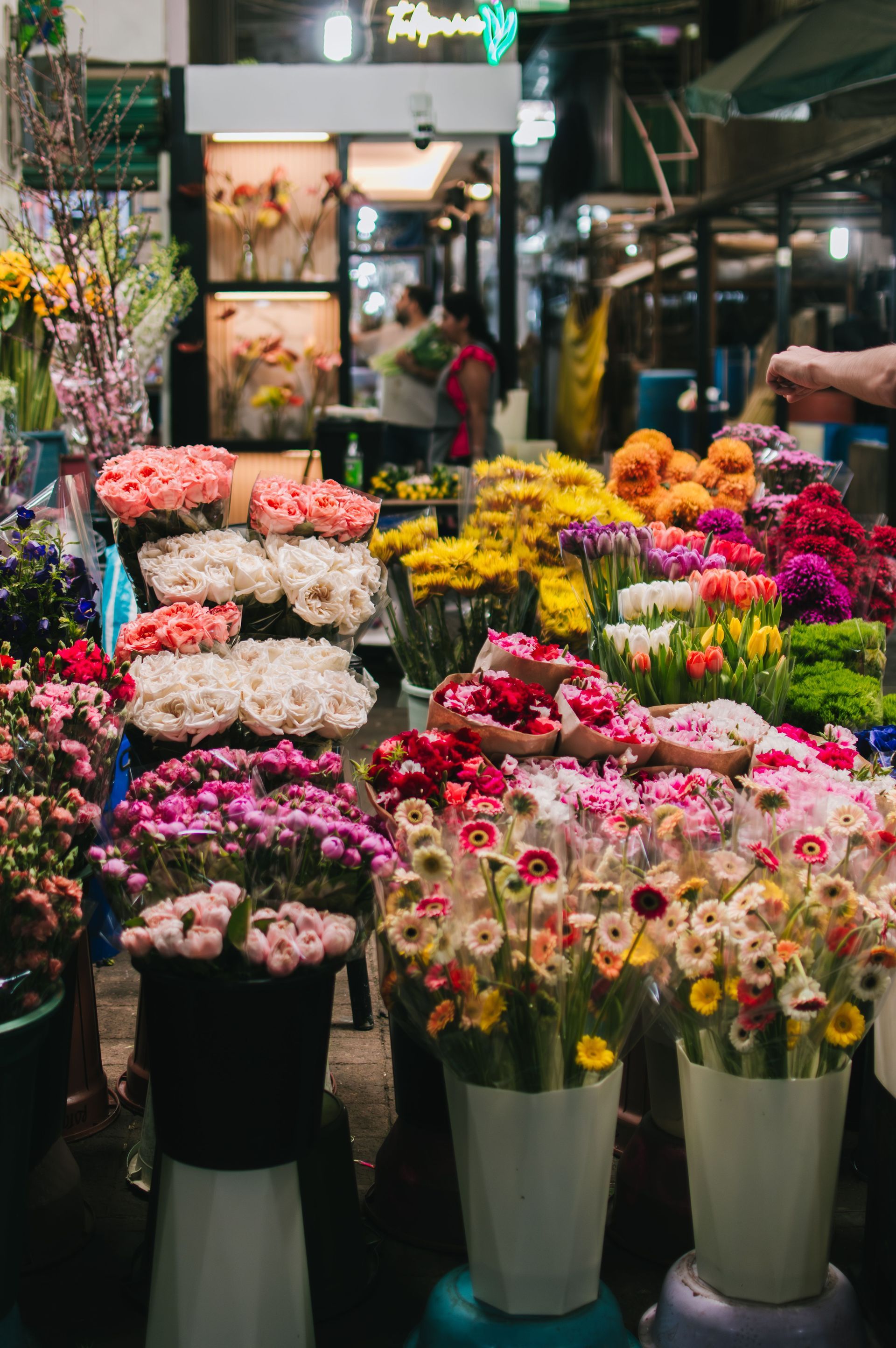 Colorful bouquets of flowers displayed in a market stall with a person browsing in the background