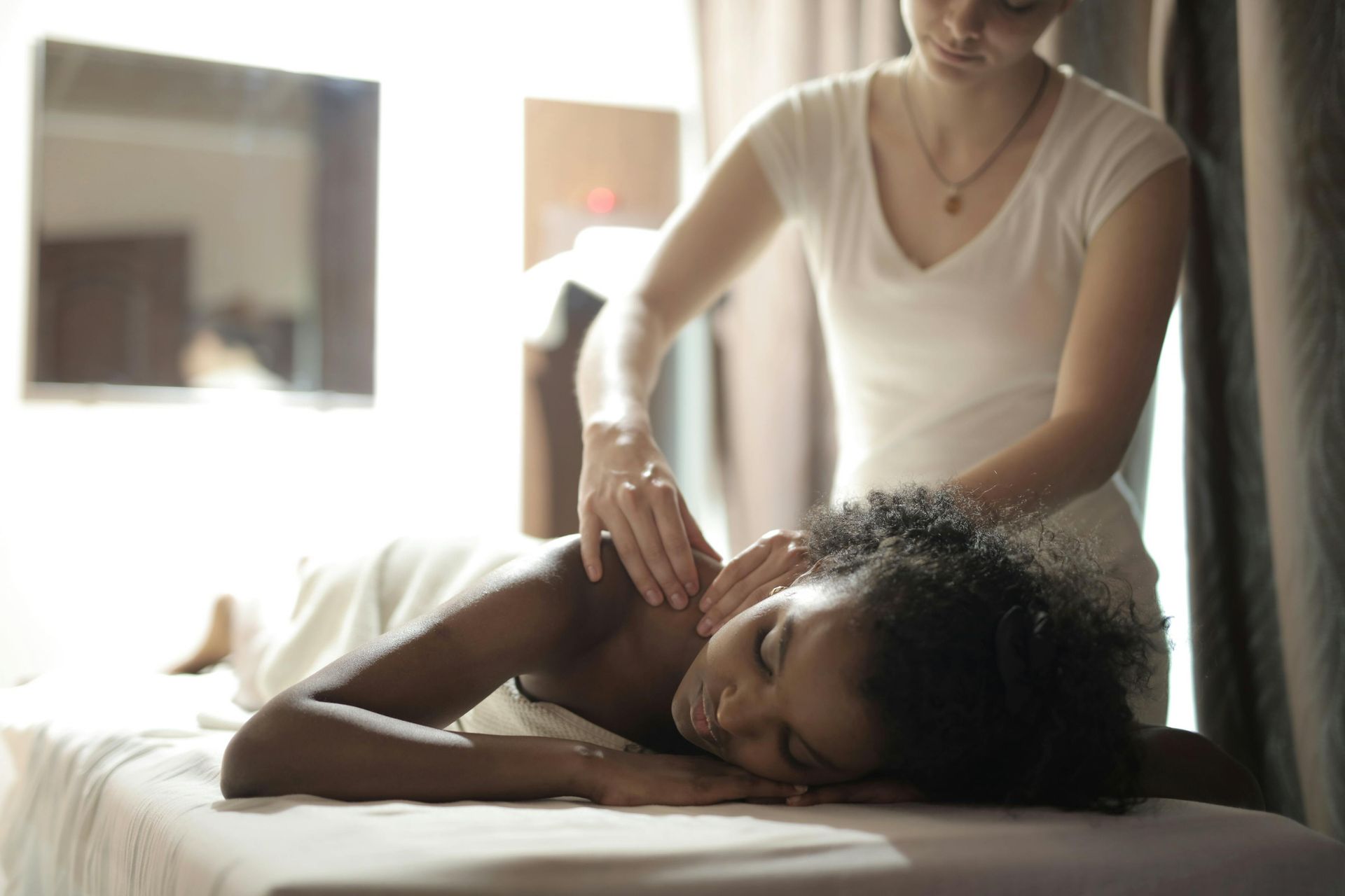 Person receiving a shoulder massage on a treatment table in a softly lit room
