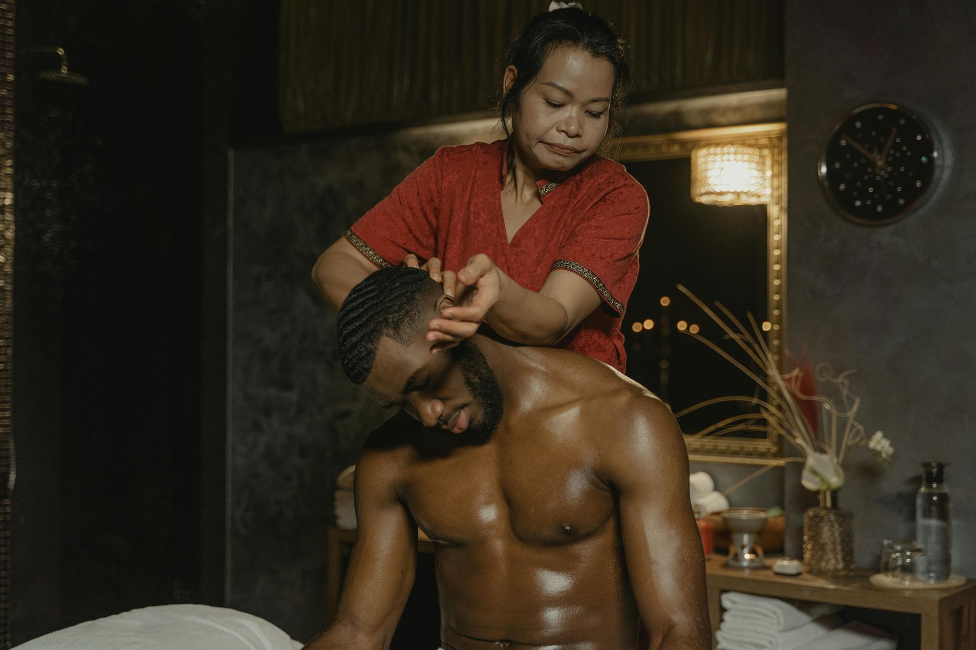 Person giving a shoulder massage in a dimly lit spa-like room
