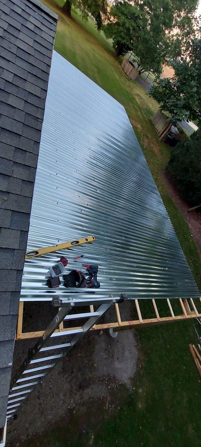 Roofing work in progress, installing corrugated metal roofing on a residential structure.