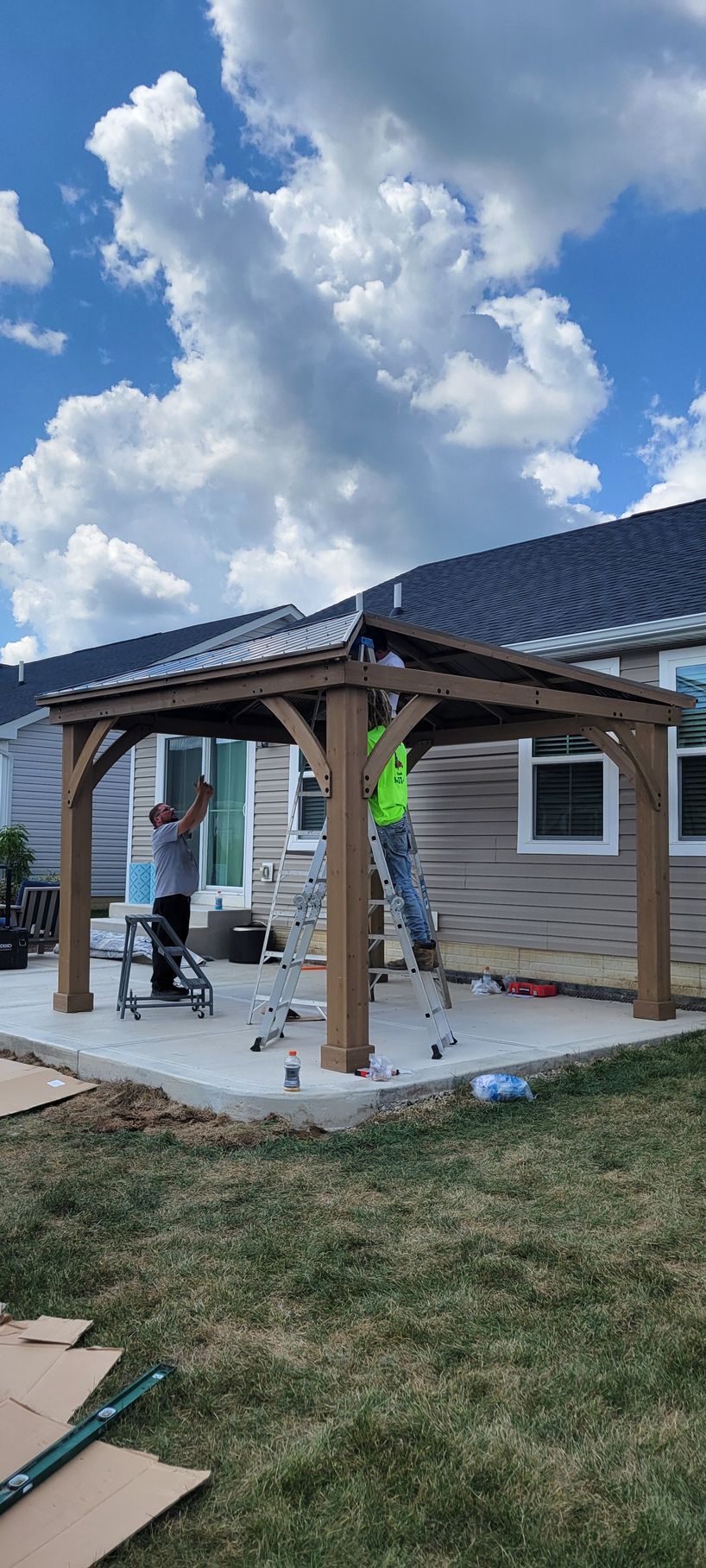 A man is painting a gazebo in front of a house.