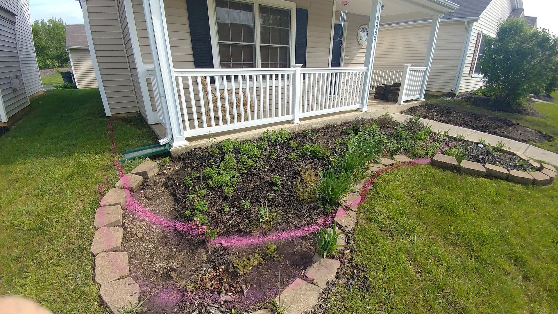 A house with a porch and a garden in front of it.