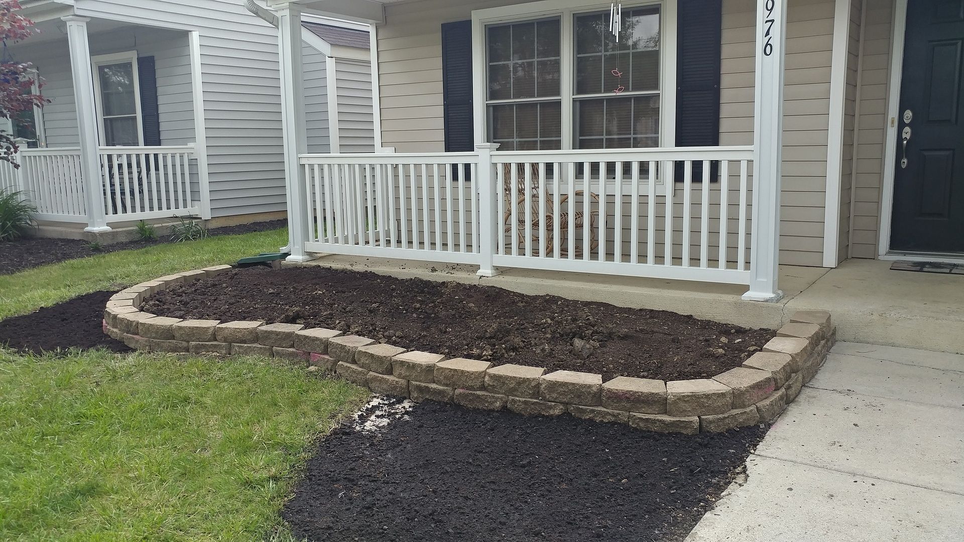 A house with a porch and a planter in front of it.