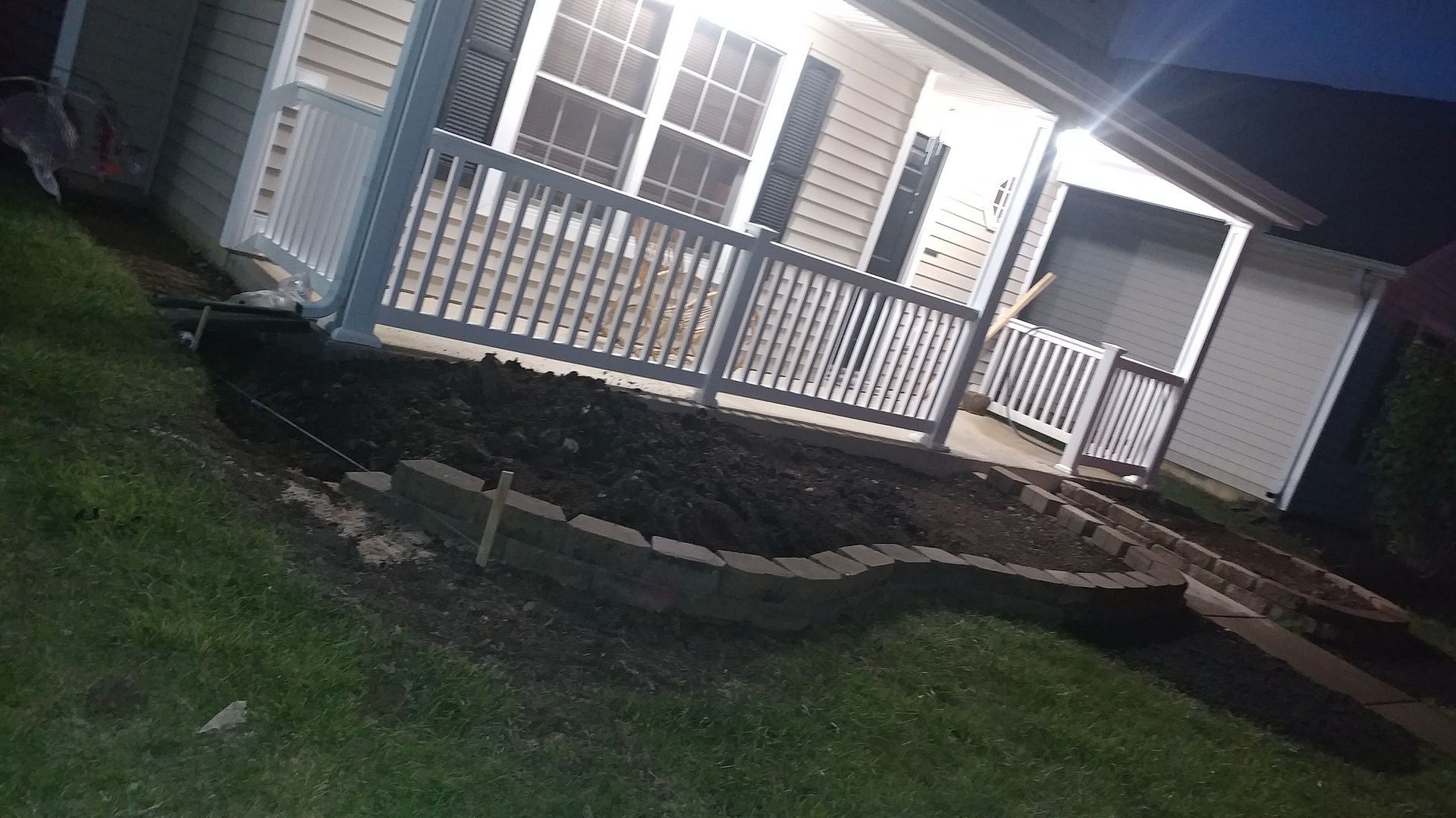 A house with a porch and a walkway is lit up at night.
