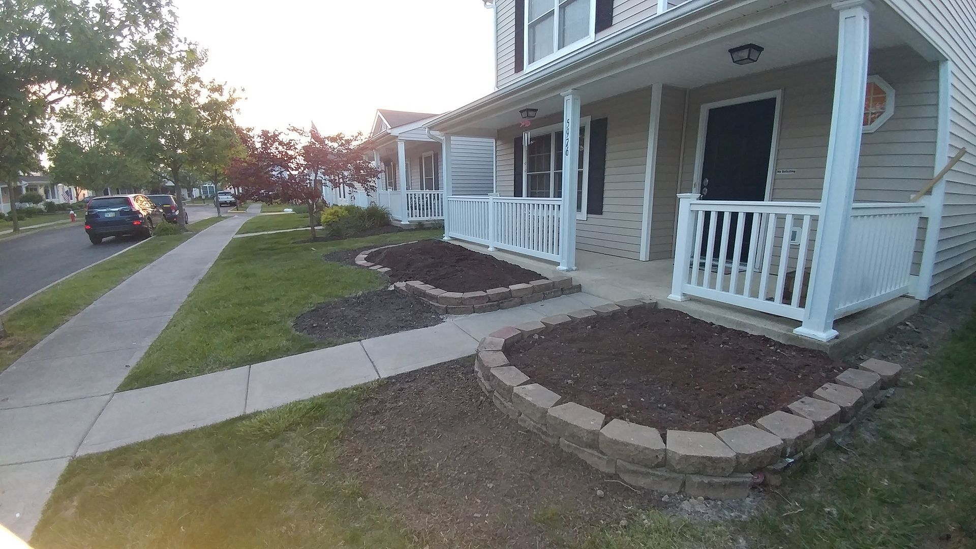 A house with a porch and a sidewalk in front of it.