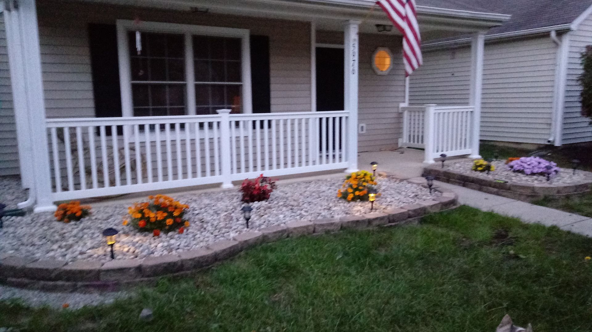 A house with a porch and flowers in front of it.