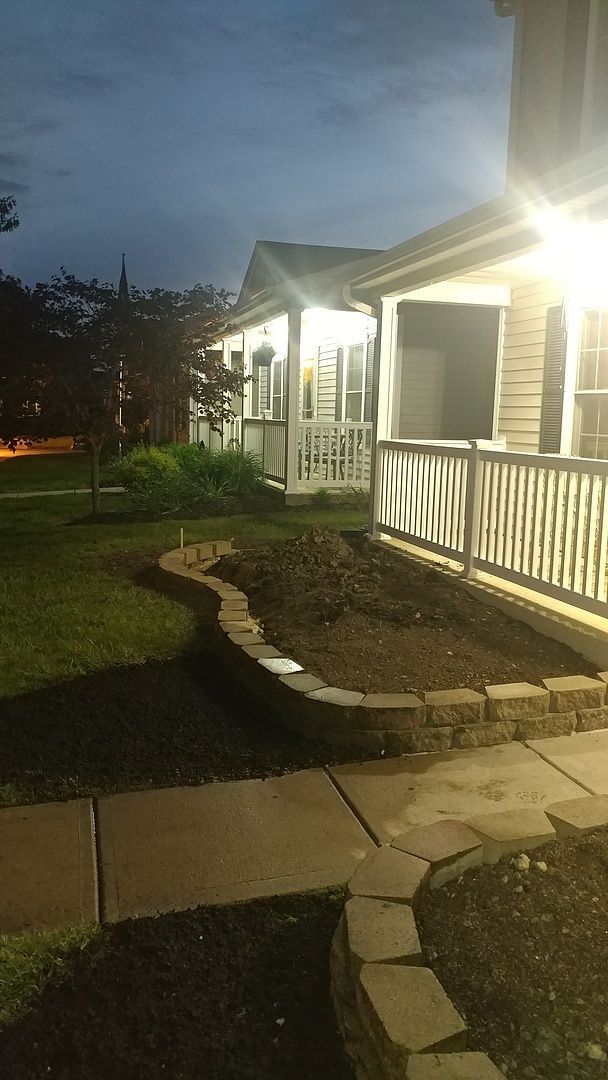 A house with a porch and a walkway is lit up at night.