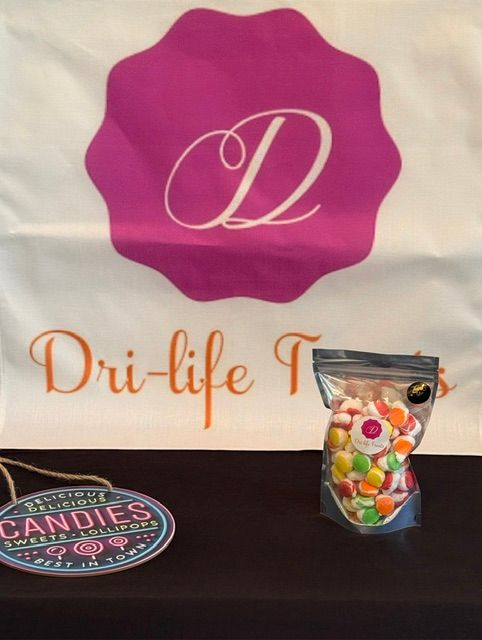 Dri-life display with magenta logo banner, candy jar, and round candy tin on a table
