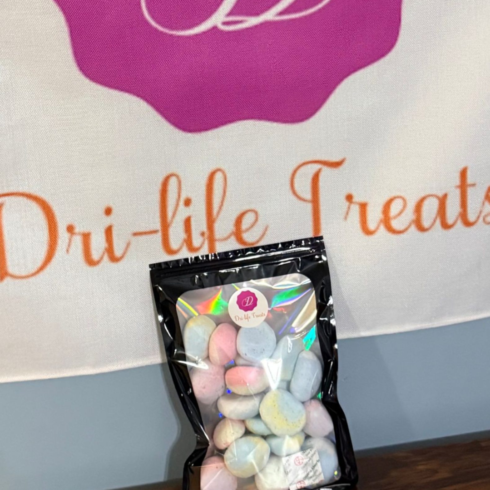 Clear bag of pastel candies on a table in front of a Dri-life Treats banner.