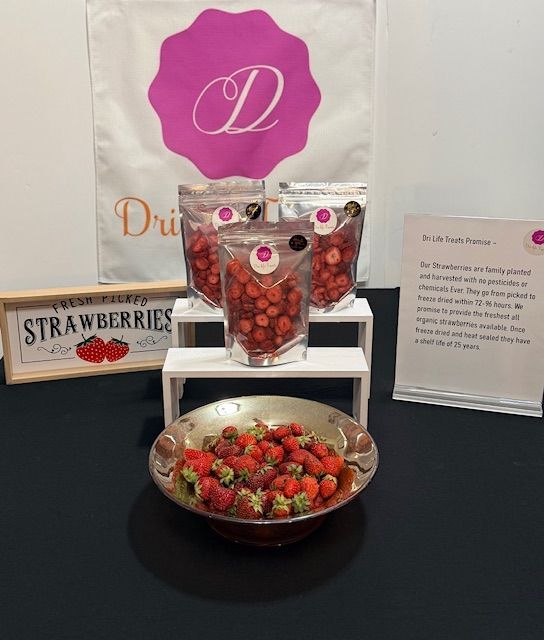 Strawberry display with packaged berries and a bowl of fresh strawberries on a table.