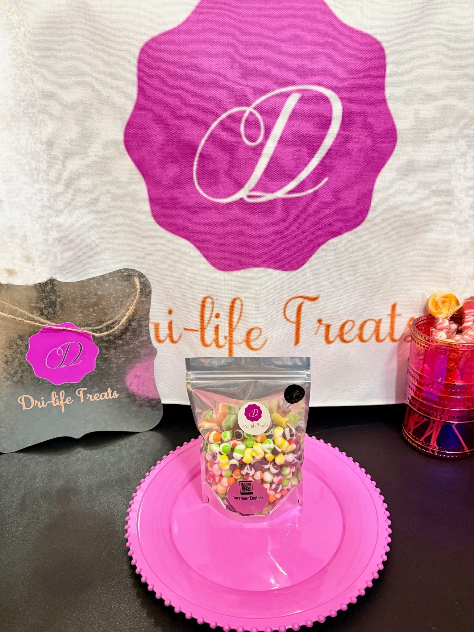 Pink dessert display with branded logo, a clear cup of sweets on a pink tray, and decorative packaging.
