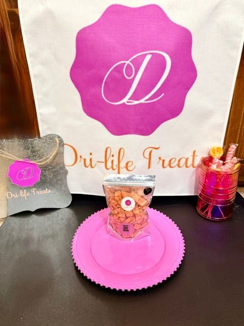 Pink dessert display with logo backdrop, cupcake on a pink plate, and decorative treats on a table