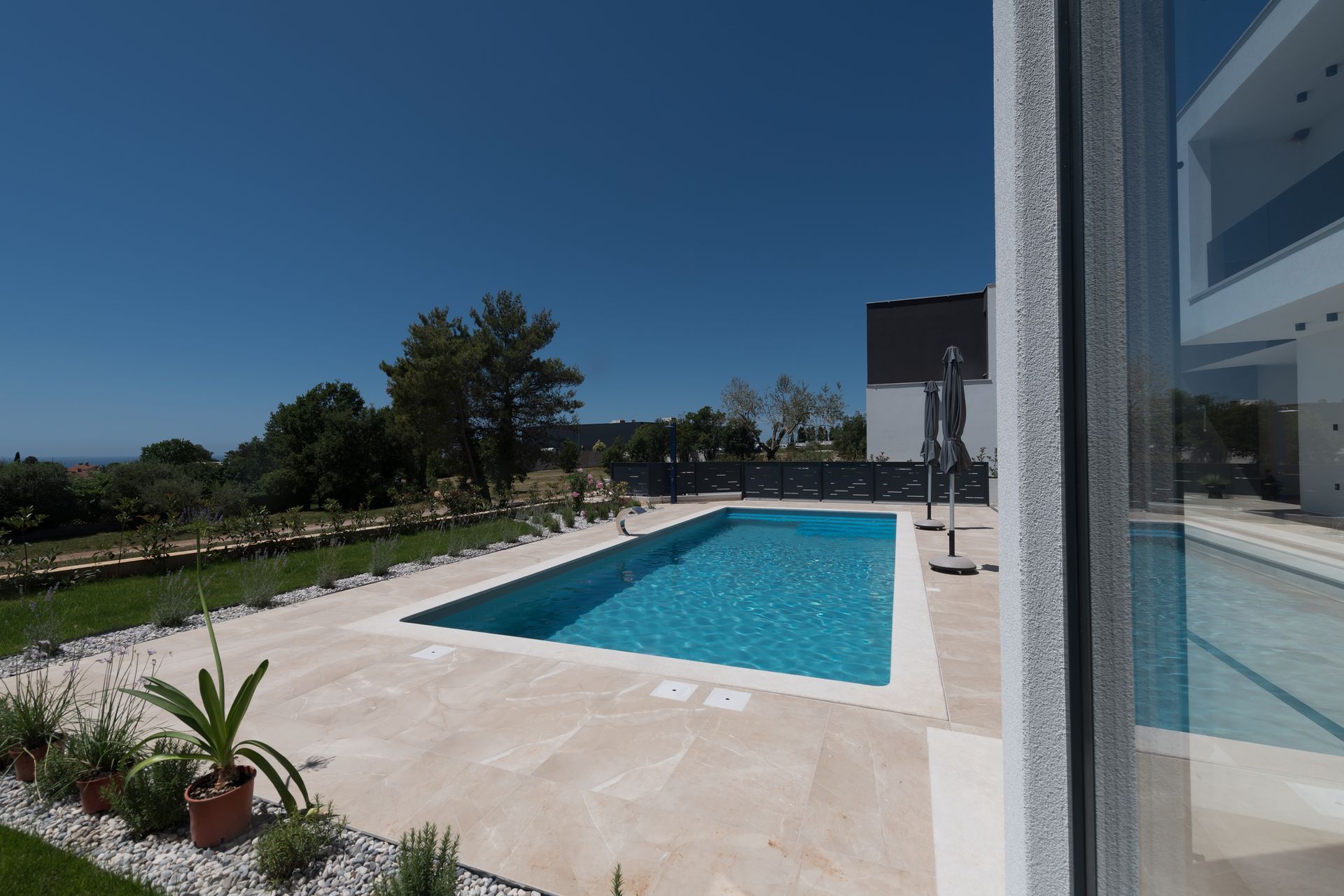 Pool overlooking a lake, surrounded by screen enclosure, plants, and patio.