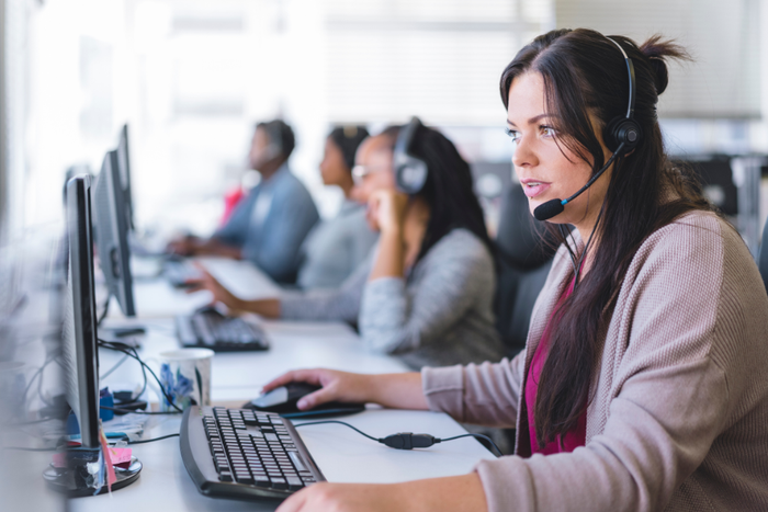 a woman with a headset sits at a computer in a monitoring centre