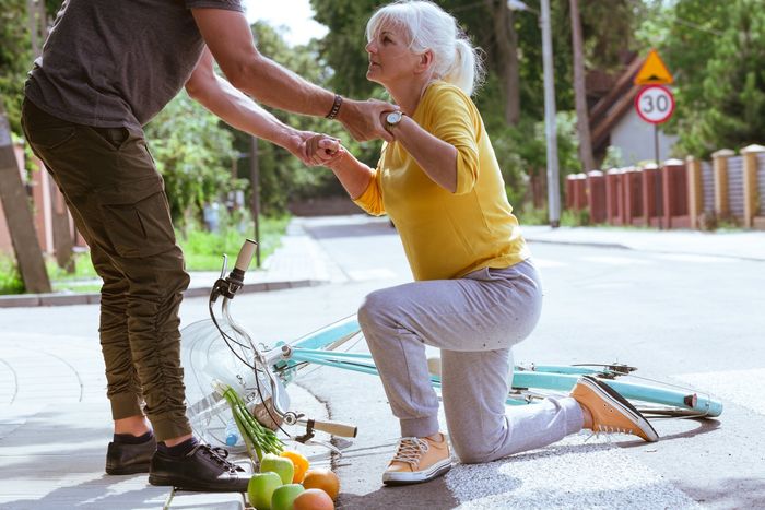 a woman is helped up from the ground after falling from her bicycle