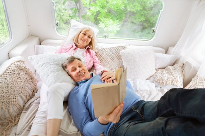 a couple lays and reads together in a RV
