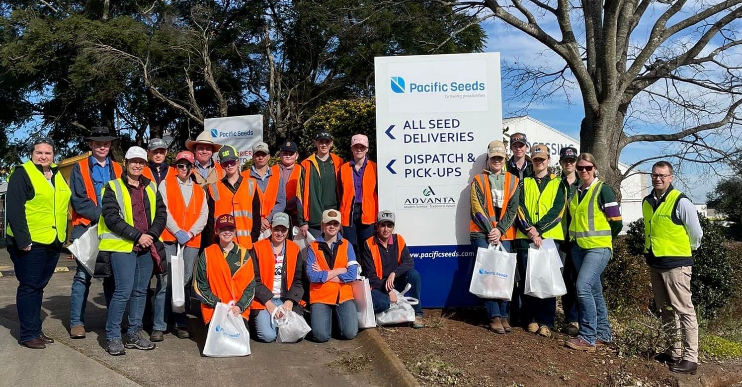 Group of volunteers in high-visibility vests posing outdoors beside a sign at a cleanup site