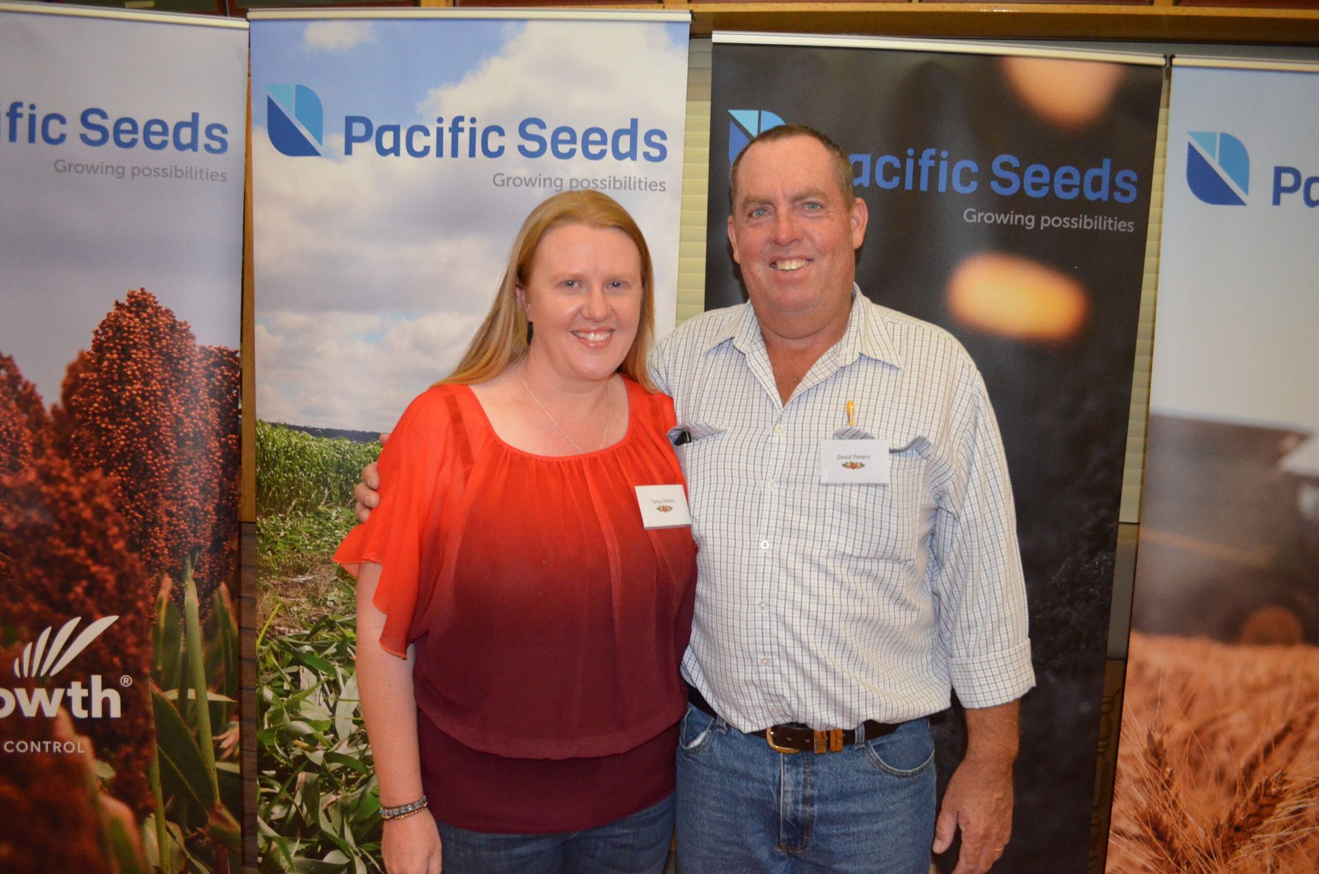 Two people smiling at a Pacific Seeds booth with branded banners in the background