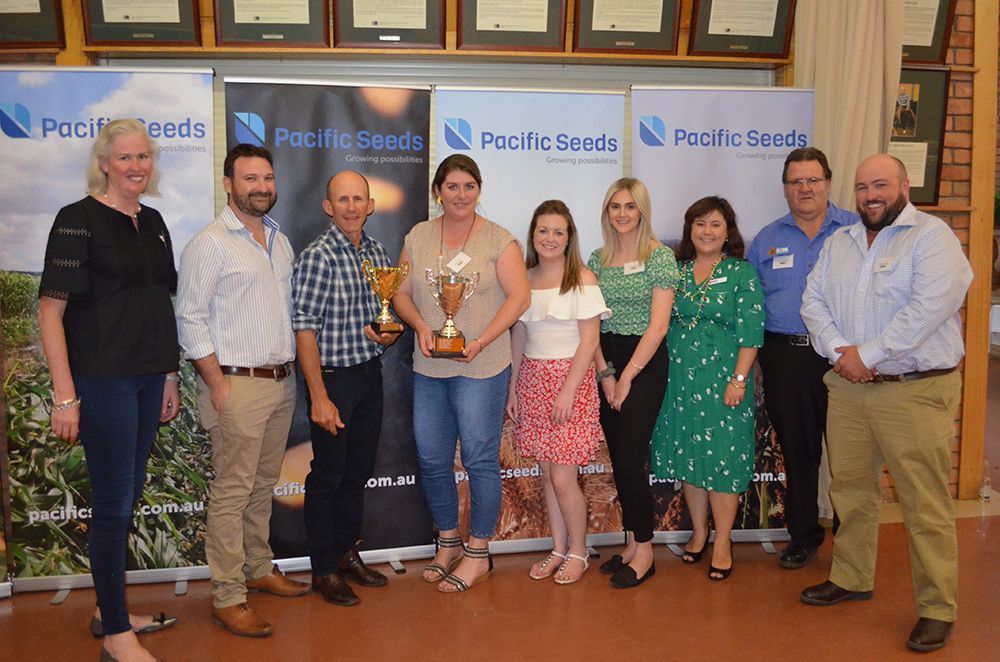 Group posing with a trophy at a Pacific Seeds/Pacific Grown event backdrop