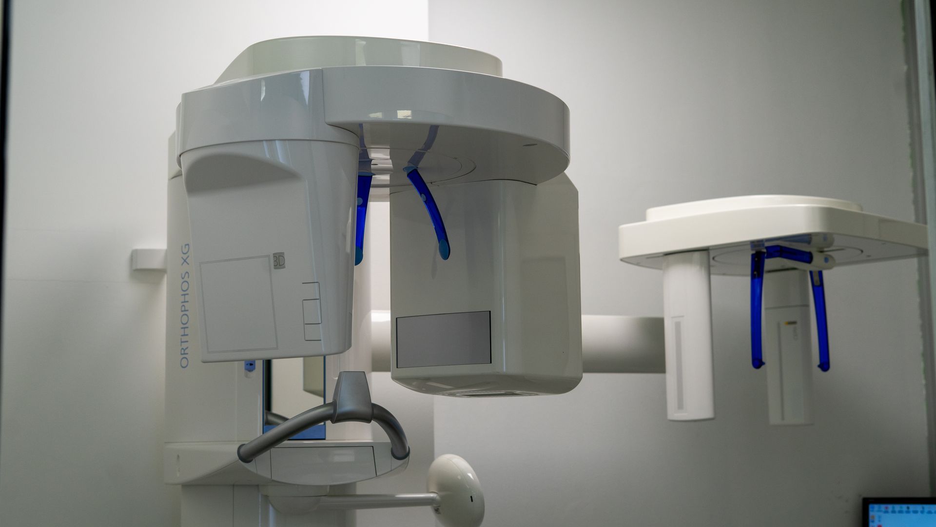 In una clinica, due apparecchi radiografici dentali, uno grande e uno più piccolo, entrambi bianchi con dettagli blu.