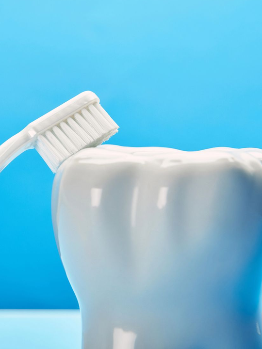Spazzolino da denti che tocca un dente bianco su sfondo blu