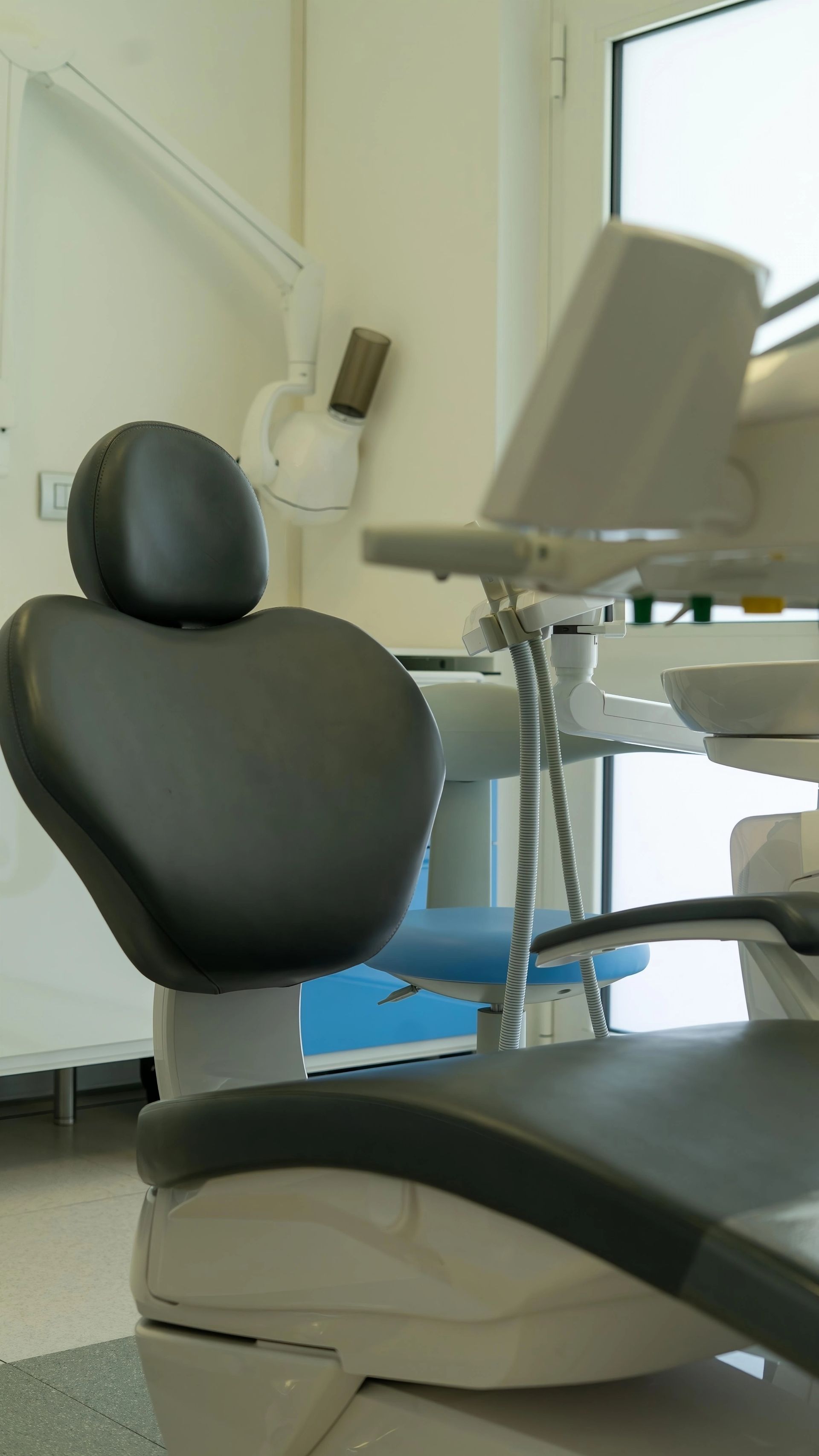 Poltrona odontoiatrica in una clinica con monitor e finestra sullo sfondo.