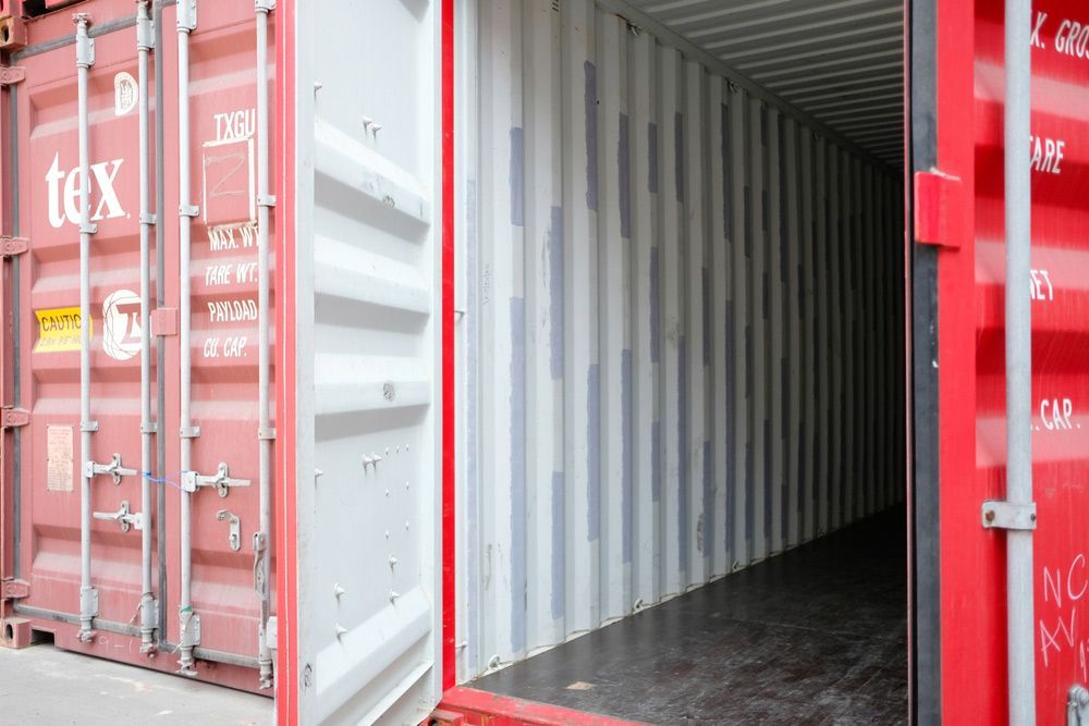 Open red shipping container with its doors swung wide, showing an empty, clean interior.