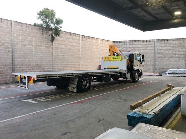A Flatbed Truck With a Crane on the Back is Parked in a Parking Lot — O'Grady's Transport & Removals in Alstonville, NSW